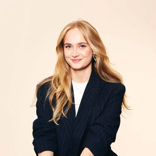 A person in a suit and blue jacket posing for the camera.